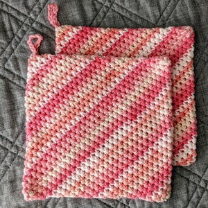 May include: Two pink and white crocheted pot holders with a diagonal pattern.
