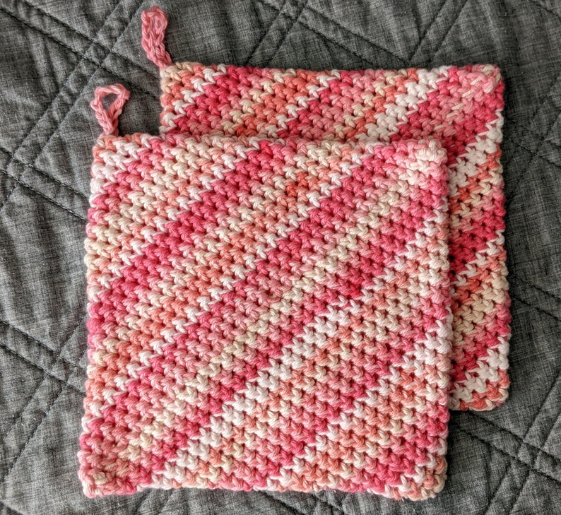 May include: Two pink and white crocheted pot holders with a diagonal pattern.