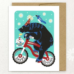 May include: A black bear wearing a party hat rides a red bicycle with a birthday cake on the handlebars. A blue bird sits on the bear's back. The bicycle wheels have the words "happy" and "birthday" written on them.