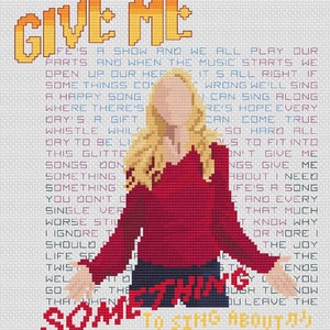May include: Cross-stitch pattern featuring a woman with blonde hair and a red shirt. The text reads "Give me something to sing about!" and includes lyrics about life, music, and finding joy in the little things.