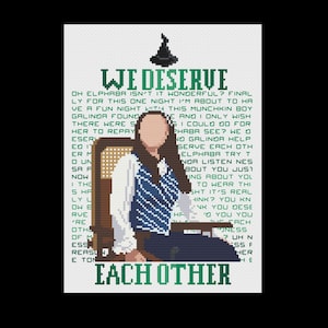 May include: A green and white cross-stitch pattern featuring a woman in a blue and white striped shirt sitting on a chair. The text "WE DESERVE EACH OTHER" is in green letters.