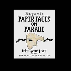 May include: A white cross-stitch pattern with black text that reads "Masquerade Paper Faces on Parade" and "Hide your face so the world will never find you". A white mask with gold accents is in the center of the pattern.