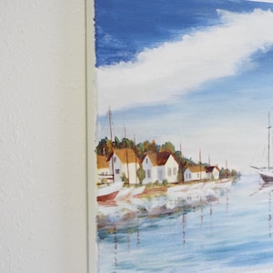 May include: A painting depicting a seascape with white houses and boats moored along the shore. The sky is blue with white clouds and the water is a light blue.