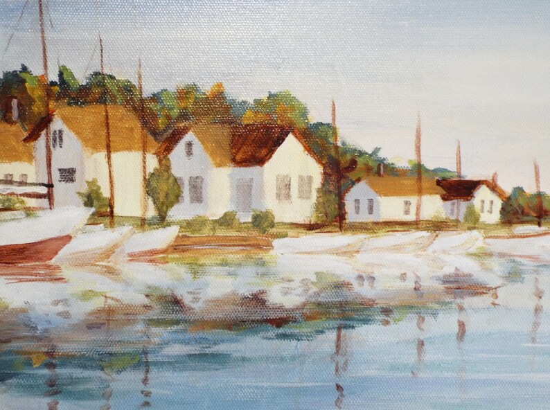 May include: A painting depicting a waterfront scene with white houses and sailboats in a harbour. The houses have brown roofs and are lined up along the water's edge. The sailboats are docked in the water, and their reflections are visible in the water.
