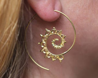 May include: Gold spiral hoop earrings with a delicate, intricate design. The earrings are made of a thin wire and have a circular shape.