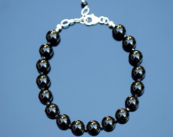 Può includere: Un braccialetto di perline di onice nero con chiusura in argento. Le perline sono rotonde e lisce, e il braccialetto è lungo circa 18 cm.