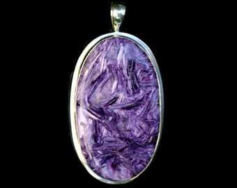 May include: A silver pendant with a large oval-shaped purple stone. The stone has a swirling, marbled pattern.