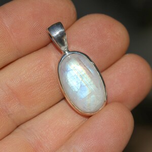 May include: A silver pendant with a white oval moonstone. The moonstone has a rainbow sheen.