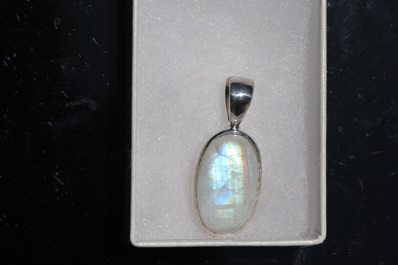 May include: A silver pendant with a white oval moonstone.