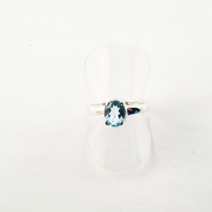 Puede incluir: Un anillo de plata con una piedra ovalada de color azul claro.