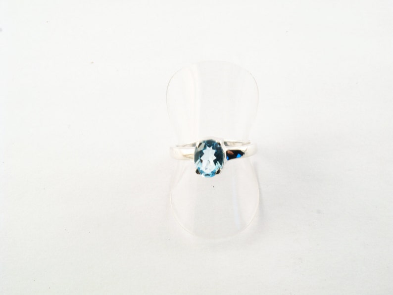 Puede incluir: Un anillo de plata con una piedra ovalada de color azul claro.
