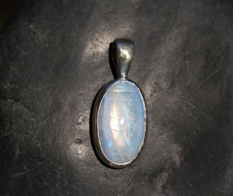 May include: A silver pendant with a white oval moonstone.