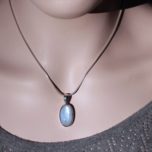May include: A silver chain necklace with a light blue oval pendant.