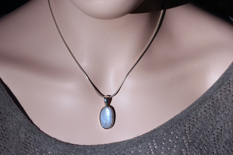 May include: A silver chain necklace with a light blue oval pendant.