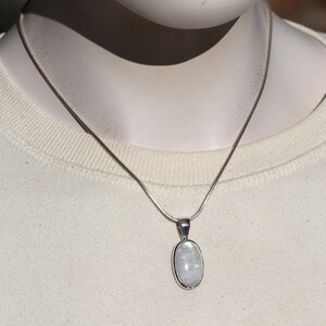 May include: A silver chain necklace with a white oval moonstone pendant.