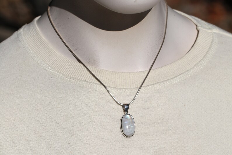 May include: A silver chain necklace with a white oval moonstone pendant.