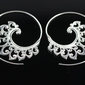 May include: A pair of silver spiral earrings with a delicate, intricate floral design.