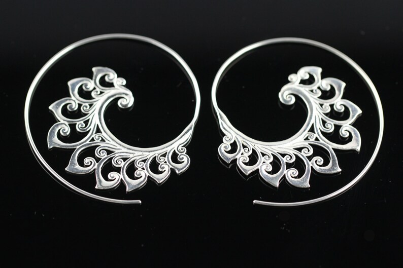 May include: A pair of silver spiral earrings with a delicate, intricate floral design.