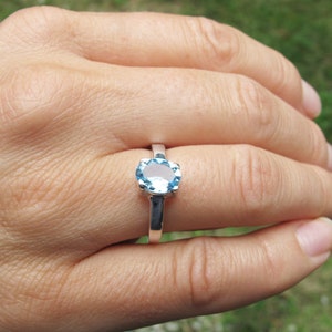Puede incluir: Un anillo de plata con una piedra ovalada azul claro.