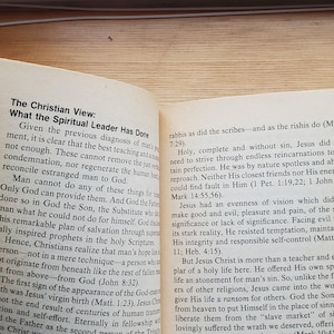 May include: Open book with text about Christian views on the spiritual leader. The text is in black font on aged, yellowed paper. The book is open to a double-page spread.