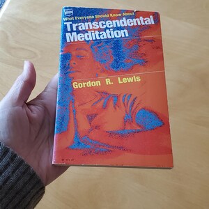 May include: A paperback book titled "What Everyone Should Know About Transcendental Meditation" by Gordon R. Lewis. The cover features a person in meditation with blue and orange hues.