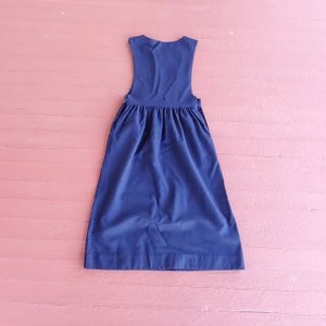 May include: A navy blue sleeveless dress with a gathered waistline. The dress is made of a smooth, lightweight fabric.