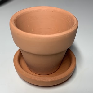 May include: A terracotta flower pot with a matching saucer. The pot is unglazed and has a natural brown color.