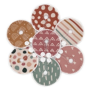 May include: Set of seven fabric circles with different patterns in shades of brown, pink, and green. Each circle has a hole in the center and a white trim around the edge.