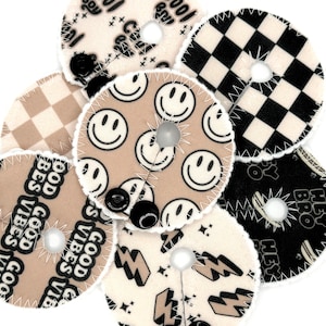 May include: A set of six round fabric patches with different designs. The patches are beige with black designs. The designs include smiley faces, checkered patterns, lightning bolts, and the phrase "Good Vibes".
