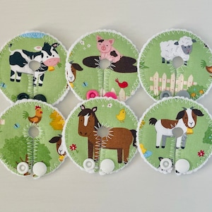 May include: Six round green fabric patches with white stitching and white buttons. Each patch features a different farm animal: a cow, pig, sheep, rooster, horse, and goat.