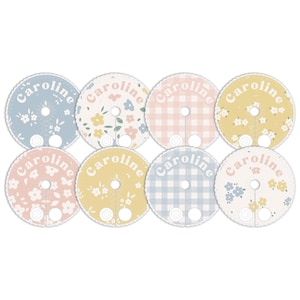 May include: Eight round, pastel-colored labels with the name "Caroline" printed in a retro font. Each label features a different pattern, including floral, gingham, and polka dots.