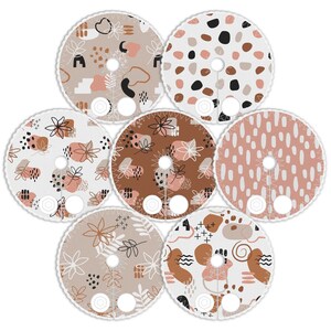 May include: Six round fabric patches featuring various abstract patterns in shades of brown, pink, and white. The designs incorporate geometric shapes, dots, and floral motifs.