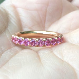 May include: A delicate gold band ring with a row of pink sapphires.