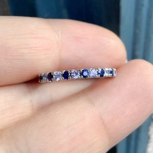 Könnte beinhalten: Ein zarter Silberring mit einer abgestuften Reihe von blauen und violetten Edelsteinen.