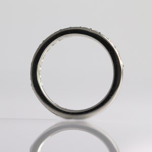 May include: A silver band with a row of small, clear stones set around the edge.