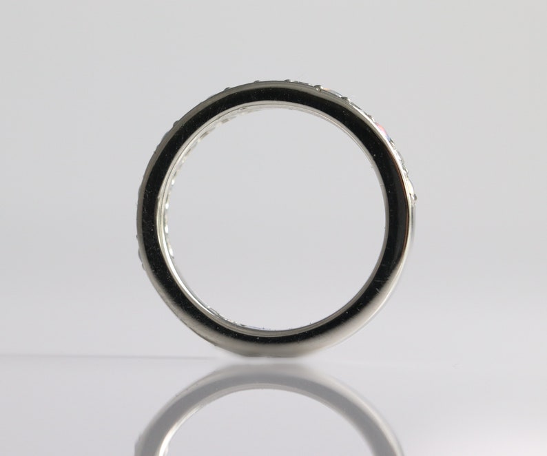 May include: A silver band with a row of small, clear stones set around the edge.