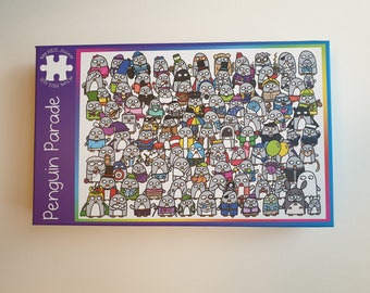 May include: A 500-piece jigsaw puzzle titled "Penguin Parade." The puzzle box features a colorful border and a purple background with the title in white. The puzzle image shows a large group of cartoon penguins in various outfits and poses.