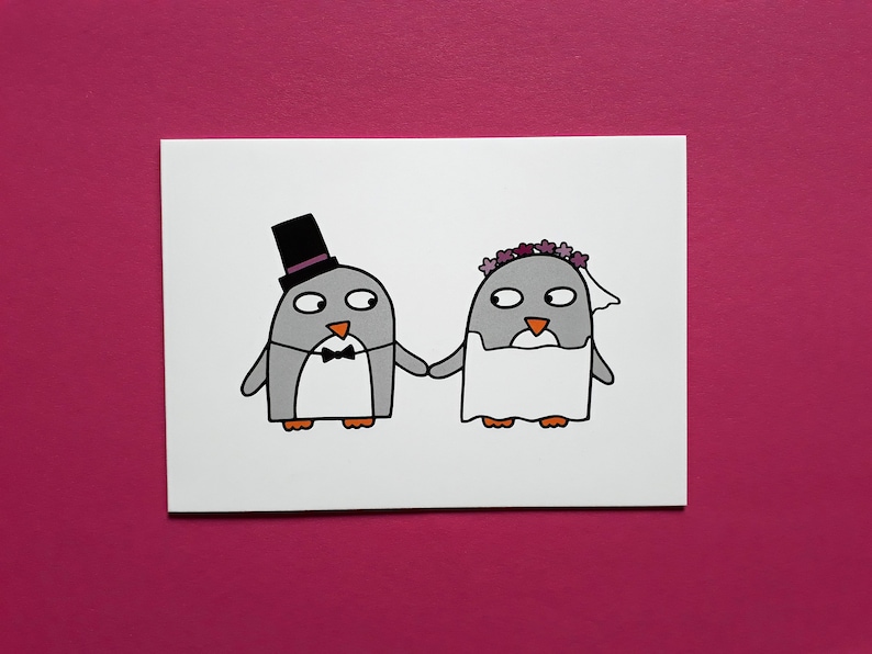 May include: A greeting card featuring a cartoon illustration of two penguins holding hands. One penguin wears a black top hat and bow tie, the other a floral crown and veil. The penguins are gray with orange feet.