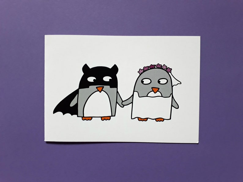 May include: A quirky illustration of two penguins holding hands. One is dressed as a bat, the other as a bride, wearing a veil and flower crown. The artwork is on a white background with a purple backdrop.