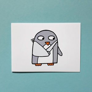 May include: A cartoon illustration of a penguin with a white bandage on its wing. The penguin is grey with an orange beak and feet. The image is on a white card against a light blue background.
