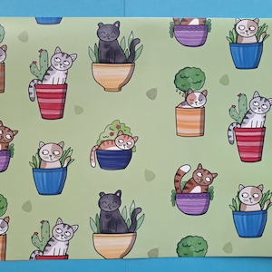 May include: A sheet of wrapping paper with a repeating pattern of cartoon cats in colorful pots. The cats are various colors, including gray, black, and orange, and the pots are in shades of blue, purple, and orange.