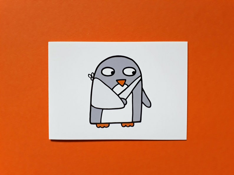 May include: A cartoon illustration of a penguin with grey and white colouring, an orange beak and feet, and a white bandage on its wing. The penguin is on a white rectangular card against an orange background.