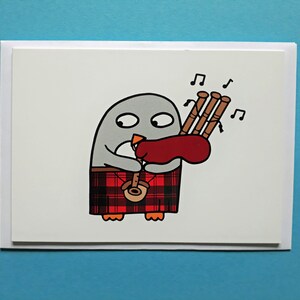 May include: A humorous greeting card illustration of a penguin playing bagpipes. The penguin is wearing a red and black tartan kilt and has a red bag. Musical notes are drawn above the bagpipes. The card is on a white background.