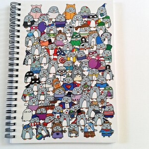 May include: A spiral-bound notebook with a vibrant illustration of many cartoon penguins. The penguins are depicted in diverse costumes, such as superheroes, pirates, and wizards. The notebook has a white background.