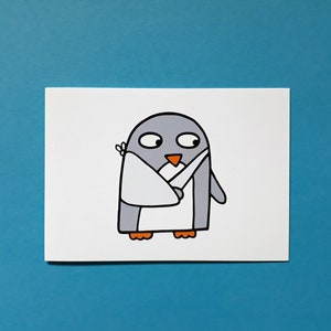 May include: A cartoon illustration of a grey penguin with an orange beak and feet, holding a knife. The penguin is wearing a white bib and has a bandage on its head. The background is a solid blue.