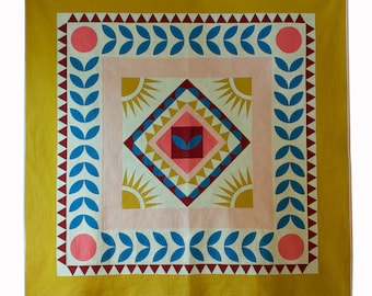 Puede incluir: Una colcha amarilla con un patrón geométrico en tonos de rosa, rojo, azul y blanco. La colcha tiene un borde de hojas y triángulos.