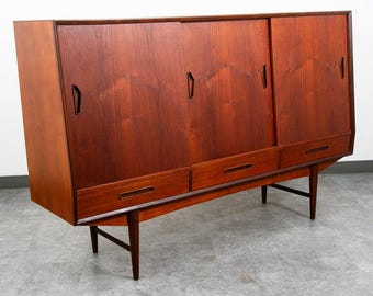 May include: A mid-century modern wooden cabinet with three sliding doors and three drawers. The cabinet is made of dark brown wood and has a sleek, minimalist design. It stands on angled legs.