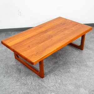 Peut inclure: Table basse rectangulaire en bois avec une finition brun-rougeâtre chaleureuse. La table a un design simple, de style moderne du milieu du siècle, avec des pieds inclinés. La table mesure environ 122 cm de long et 51 cm de large.