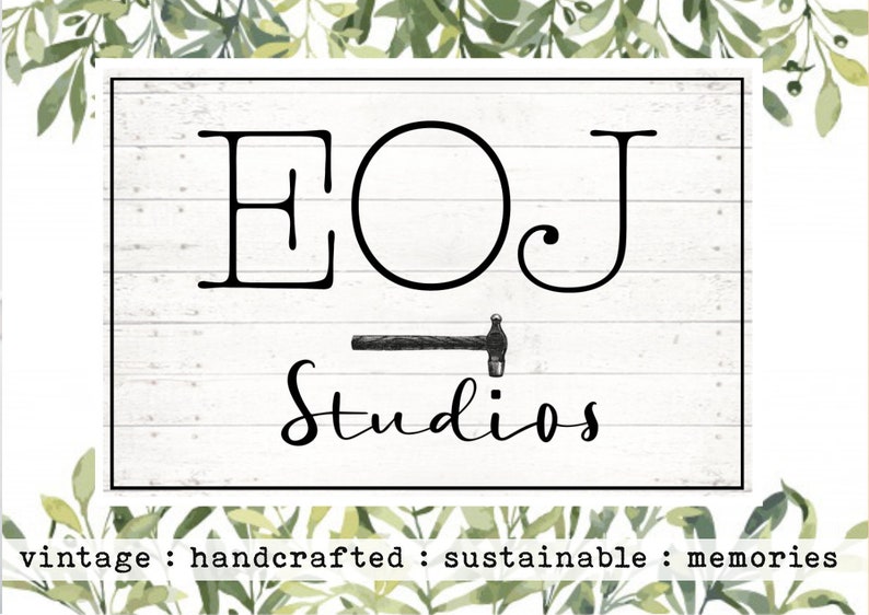 K&ouml;nnte beinhalten: Ein wei&szlig;es Holzschild mit schwarzem Text, der "EOJ Studios" lautet, mit einer kleinen schwarzen Hammergrafik unter dem Text. Der Text "vintage : handcrafted : sustainable : memories" ist unter dem Schild gedruckt.