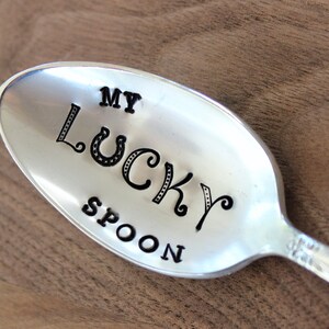 Puede incluir: Una cuchara de plata con las palabras "My Lucky Spoon" grabadas.
